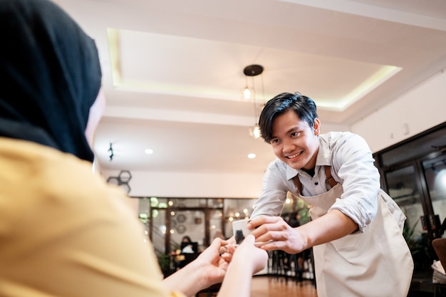 Serveerster die een kopje koffie aanbiedt voor de klant van het meisje in de coffeeshop