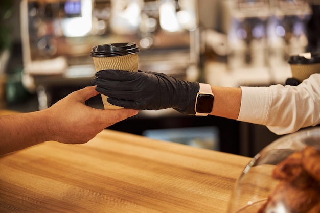 Serveerster in rubberen handschoenen die de bestelling aan haar bezoeker geeft