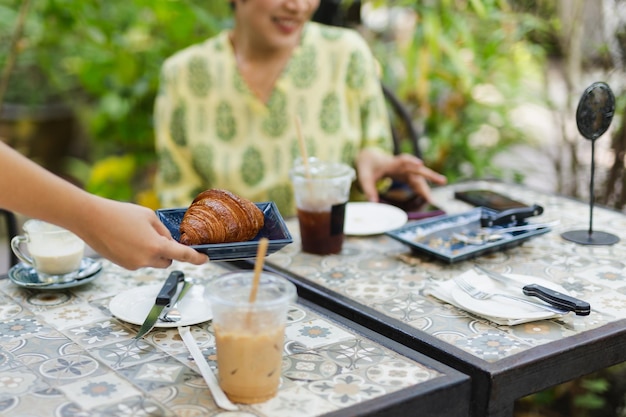 Serveerster serveert croissants in de coffeeshop buiten