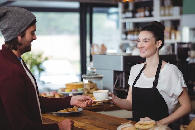 Serveerster serveert een kopje koffie aan de klant