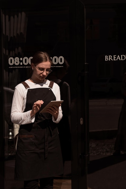 Serveerster staat in de zomer buiten met een tablet in haar handen