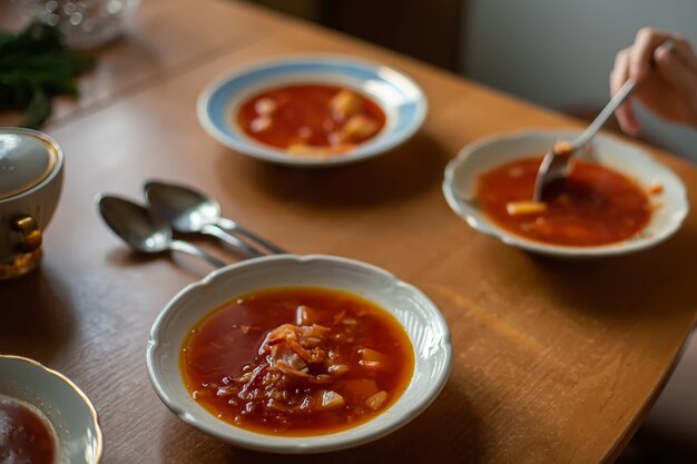 Serveertafel voor lunch in familie. Oekraïense keuken. Rode soepborsch in witte borden.