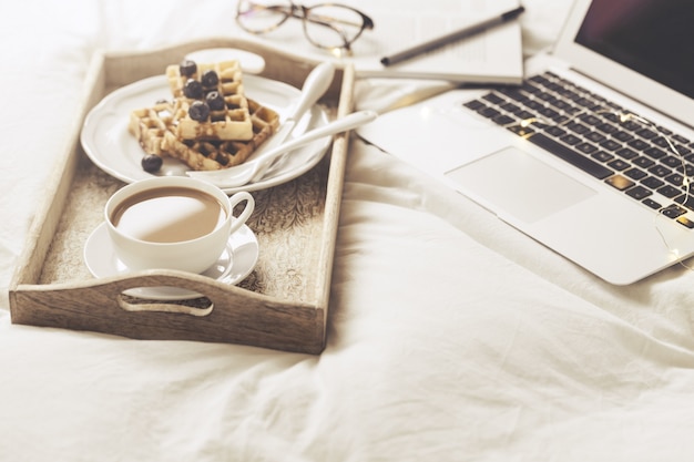 Photo server with breakfast and laptop on bed