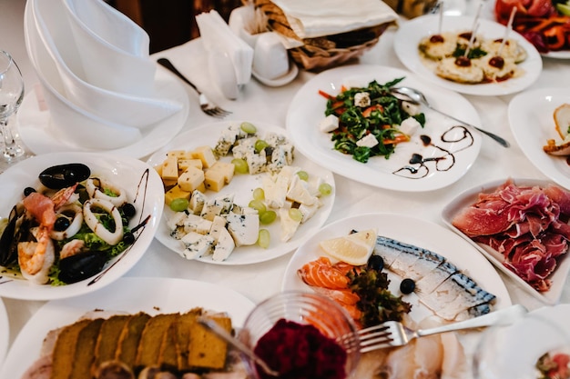 お祝いのテーブルで夕食を提供しますフードサラダ肉魚の食事結婚式の宴会でお祝いのテーブル装飾の詳細