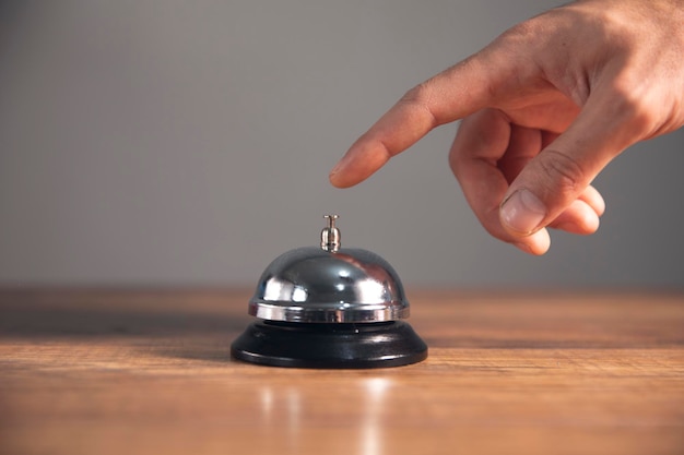 Service bell locating at wooden table touching finger