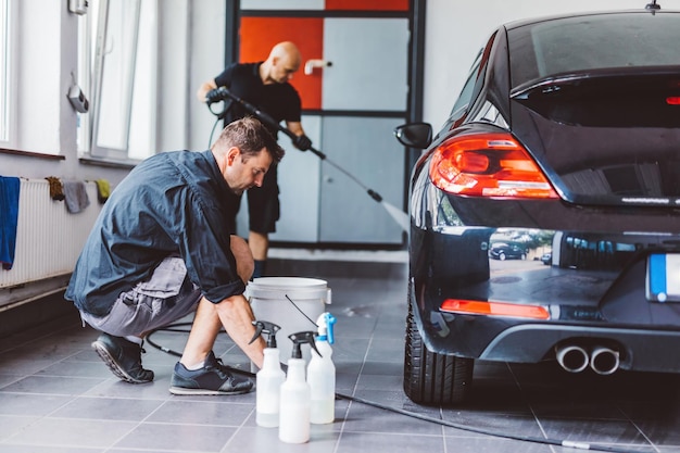 Photo service man washing car before detailing in workshop professional work