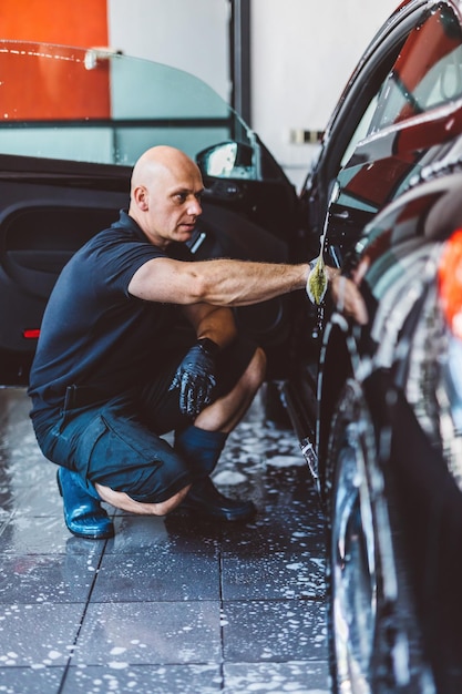 Photo service man washing car before detailing in workshop professional work