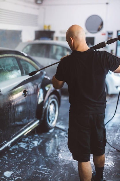 Photo service man washing car before detailing in workshop professional work