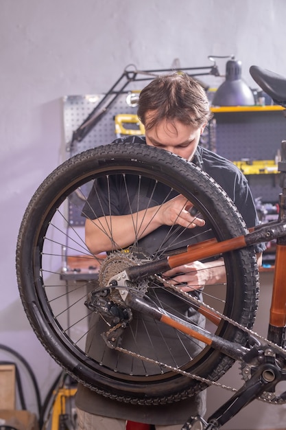 Concetto di servizio, riparazione, bici e persone - meccanico che ripara una mountain bike in un'officina