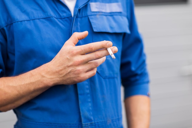 サービス、修理、メンテナンス、人々のコンセプト – タバコを吸う自動車整備士の接写