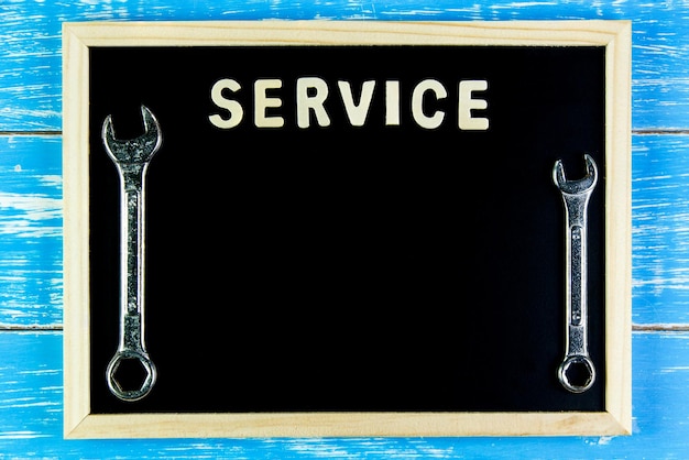 Photo service text with spanners on blackboard at wooden table