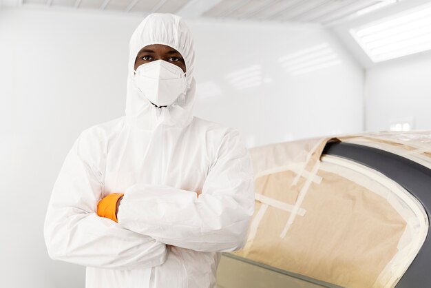 Service worker painting car in auto service