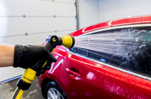 Service worker washing car on a car wash.