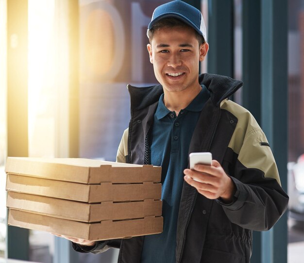 Service zo snel dat het nog steeds gloeiend heet is Portret van een jonge man die een pizza bezorgt in een kantoor