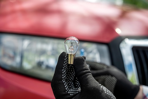 Servicevervanging van een halogeenkoplamp voor auto's Autoreparatiehand die een gloeilamp vasthoudt