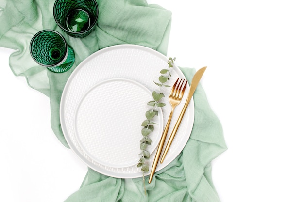 Servies en decoraties voor het serveren van een feestelijke tafel. borden, wijnglazen en bestek met grijs decoratief textiel op witte achtergrond.