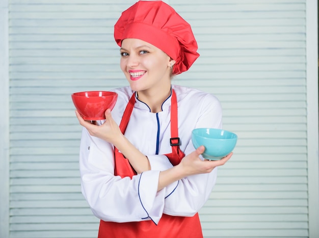 Servies keuze culinaire keuken kok in restaurant uniform professionele chef-kok koken in keuken meisje in schort en hoed houden kommen gelukkige vrouw houdt van eten maken de juiste keuze