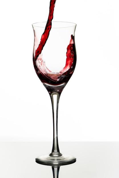 デリシャスな赤ワインと一緒に美しいグラスをお召し上がりいただけます。白い背景、ガラスのカップ。エレガンス、美味しさ、スタイルコンセプト。