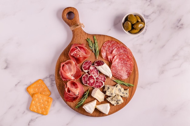 Serving board with meat and cheese snacks top view