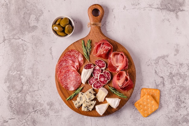 Serving board with meat and cheese snacks top view