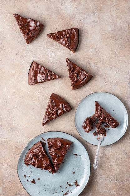 Serving brownie of triangular shape with ganache cream. Top view, flat lay, light background.