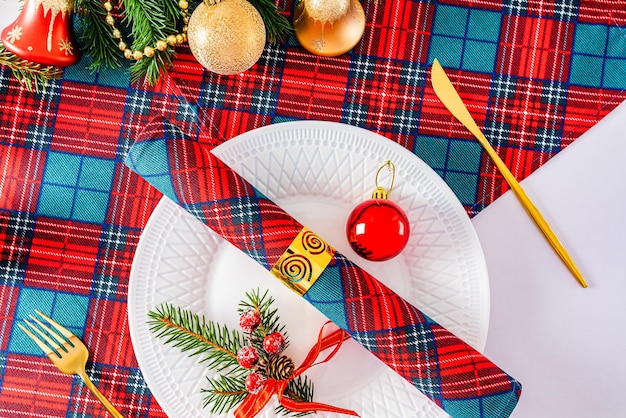 Servire la tavola di natale nei tradizionali colori di bianco rosso verde piatto bianco oro posate vista dall'alto