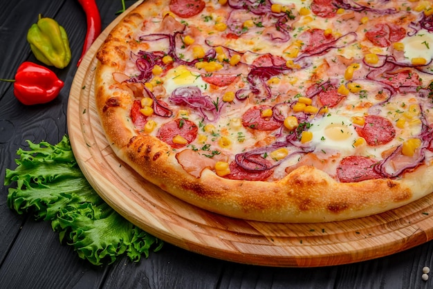 Serving delicious pizza with quail eggs ham sausage and vegetables on a black background