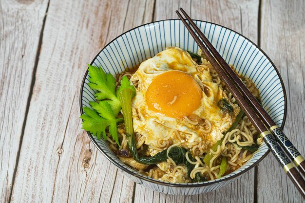 Photo a serving of instant noodle with chicken sunny side up and veggies selective focus points