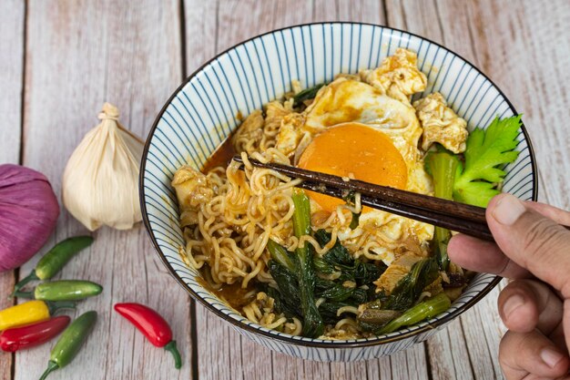 Photo a serving of instant noodle with chicken sunny side up and veggies