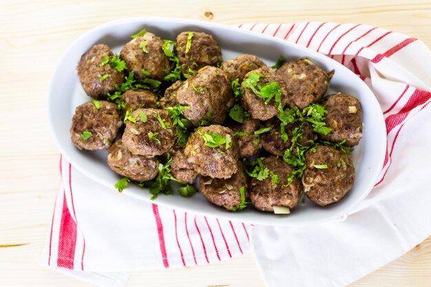 Serving large italian meatballs in a white serving dish for
dinner.