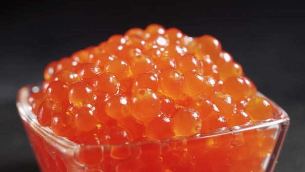 A serving of selected red caviar in a transparent glass bowl. Gourmet seafood, gourmet food. Healthy and healthy food concept.