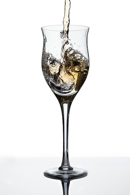 少し傾けたグラスに白ワインを添えて。白色の背景。スペースをコピーします。動き、優雅さ、味の概念。