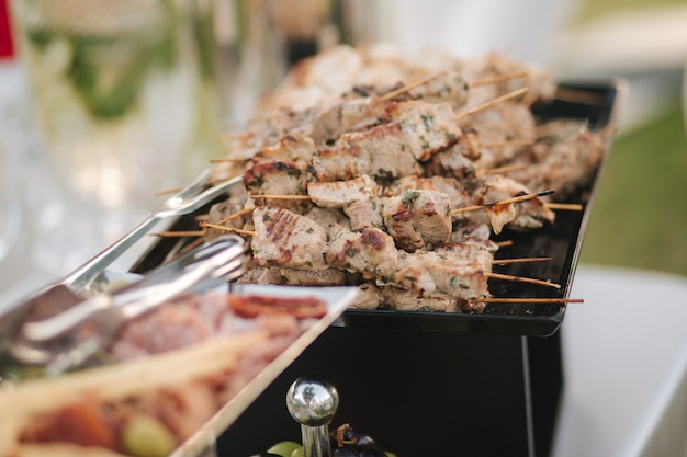 Serving small hot chicken and red fish kebabs on the buffet catering for a dinner party on the