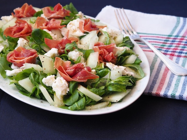 A serving of spinach melon and jamon salad