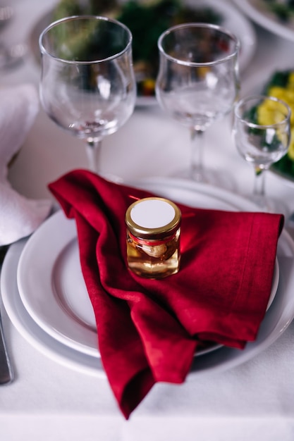 Serving table with red napkins and white tablecloth view from\
above on a plate with a beautiful presentation and a gift from the\
newlyweds honey with nuts