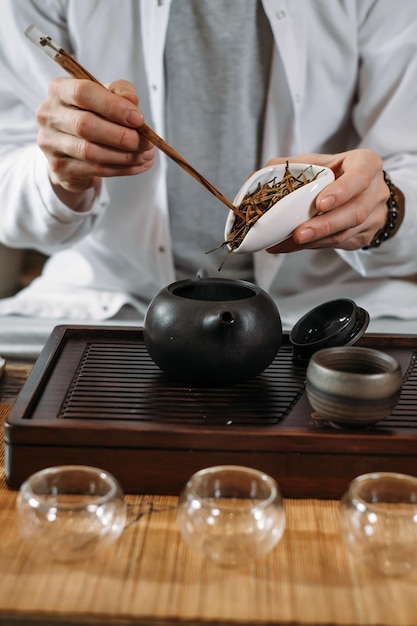 Serving traditional chinese tea ceremony and pouring oolong\
from a teapot with vapor on a dark background