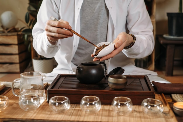 Serving traditional chinese tea ceremony and pouring oolong\
from a teapot with vapor on a dark background