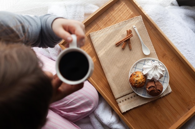 Serving tray with sweet dessert and cup of coffee in bed, white sheets, and blanket in the hotel. Romantic start of the day, coffee in bed with organic dessert.