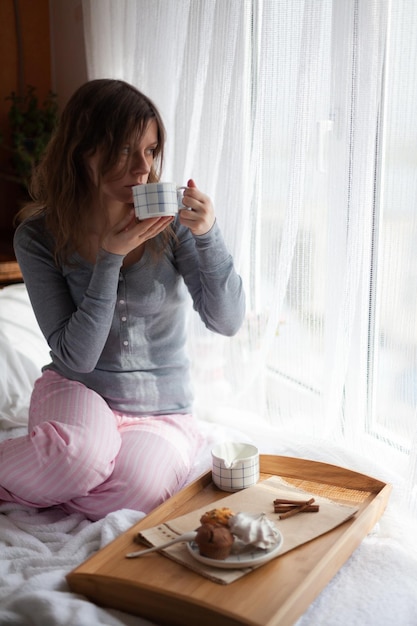 Serving tray with sweet dessert and cup of coffee in bed white sheets and blanket in the hotel