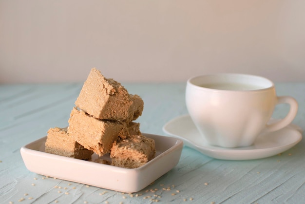 Sesam halva en kopje koffie op blauwe achtergrond. Traditionele Midden-Oosterse zoetigheden. Joods, Turks, Arabisch nationaal dessert. Turks fruit. Een plek om te kopiëren.