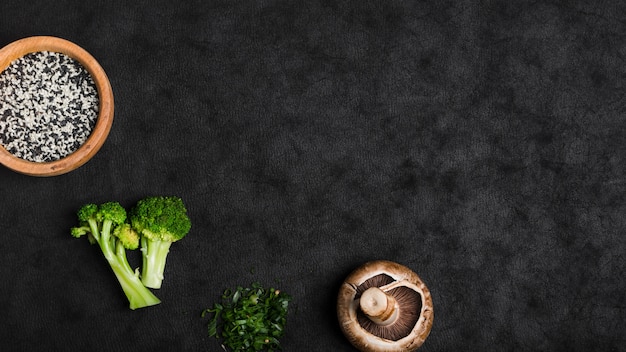 Foto sesam zaden; broccoli; paddestoel; gehakte lente-ui op zwarte textuur achtergrond