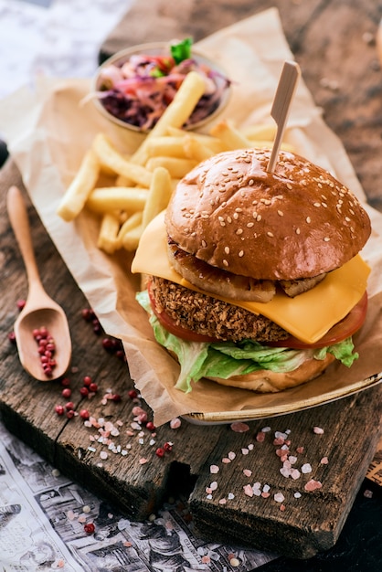 Sesamburger met ananas, kaas en frietjes op een houten snijplank.