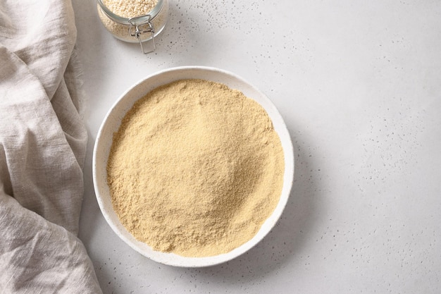 Sesame flour in white bowl and sesame seeds in spoon