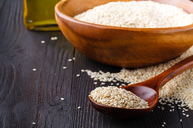 Sesame oil in glass jar and sesame seeds on wood spoon