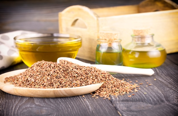 Photo the sesame oil in glass and seeds on wooden