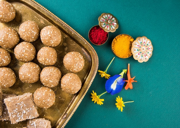 Makar Sankranti 축제를위한 꽃이있는 haldi kumkum이있는 참깨 또는 ril gul 또는 Tilgul laddu, 선택적 초점
