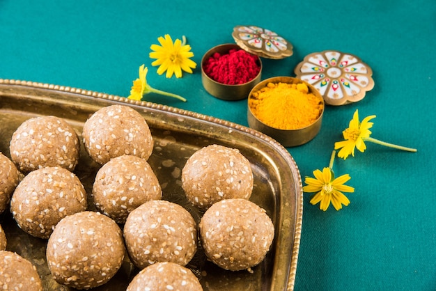 Makar Sankranti 축제를위한 꽃이있는 haldi kumkum이있는 참깨 또는 ril gul 또는 Tilgul laddu, 선택적 초점