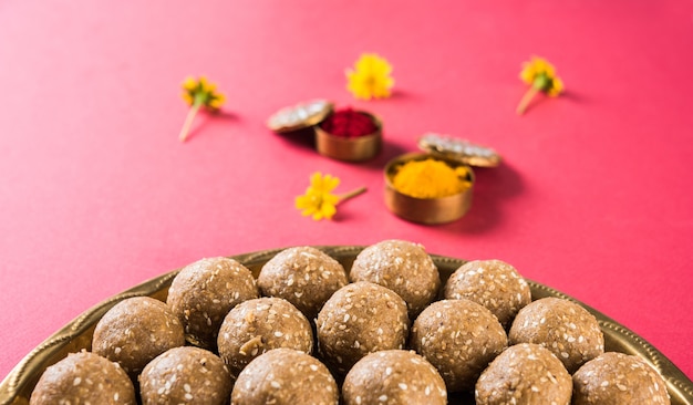 Foto sesamo o ril gul o tilgul laddu con haldi kumkum con fiori per il festival di makar sankranti, messa a fuoco selettiva