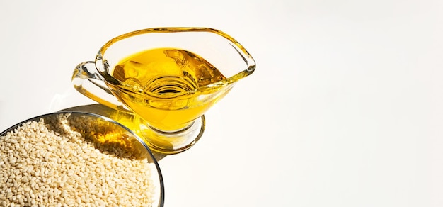 Sesame seed and oil in glass bowl close up on white background