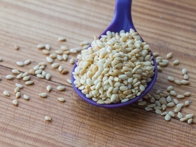 sesame seeds in plastic ladle on wooden table